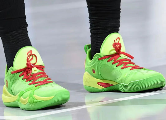 Close-up of neon green basketball shoes with red laces worn with black socks on court floor